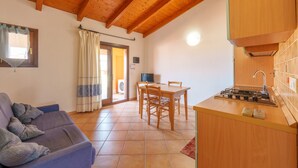 Een gezellige kamer met houten plafond, een bank, een eettafel met stoelen en een kitchenette.
