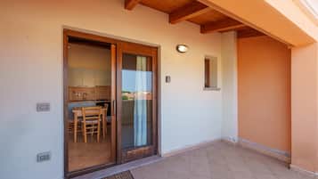 Una propiedad residencial con puerta corredera de vidrio que da a una cocina, un patio con baldosas y un techo de madera.