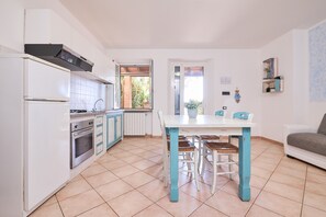 A kitchen with white cabinets, a stove, and a dining table with chairs.