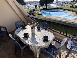 A balcony with a table set for four, overlooking a marina with boats.