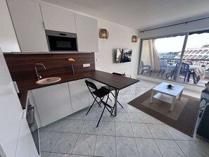 A modern kitchen with a built-in oven, a sink, and a dining area with a table and chairs.