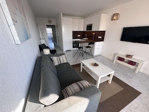A modern living room with a sofa, a coffee table, and a TV.