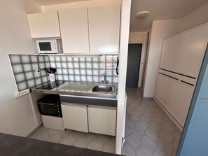 A compact kitchen with white cabinets, a stainless steel sink, and a microwave. - Sea view studio-cabin 50m from beach, private parking (Port Camargue)