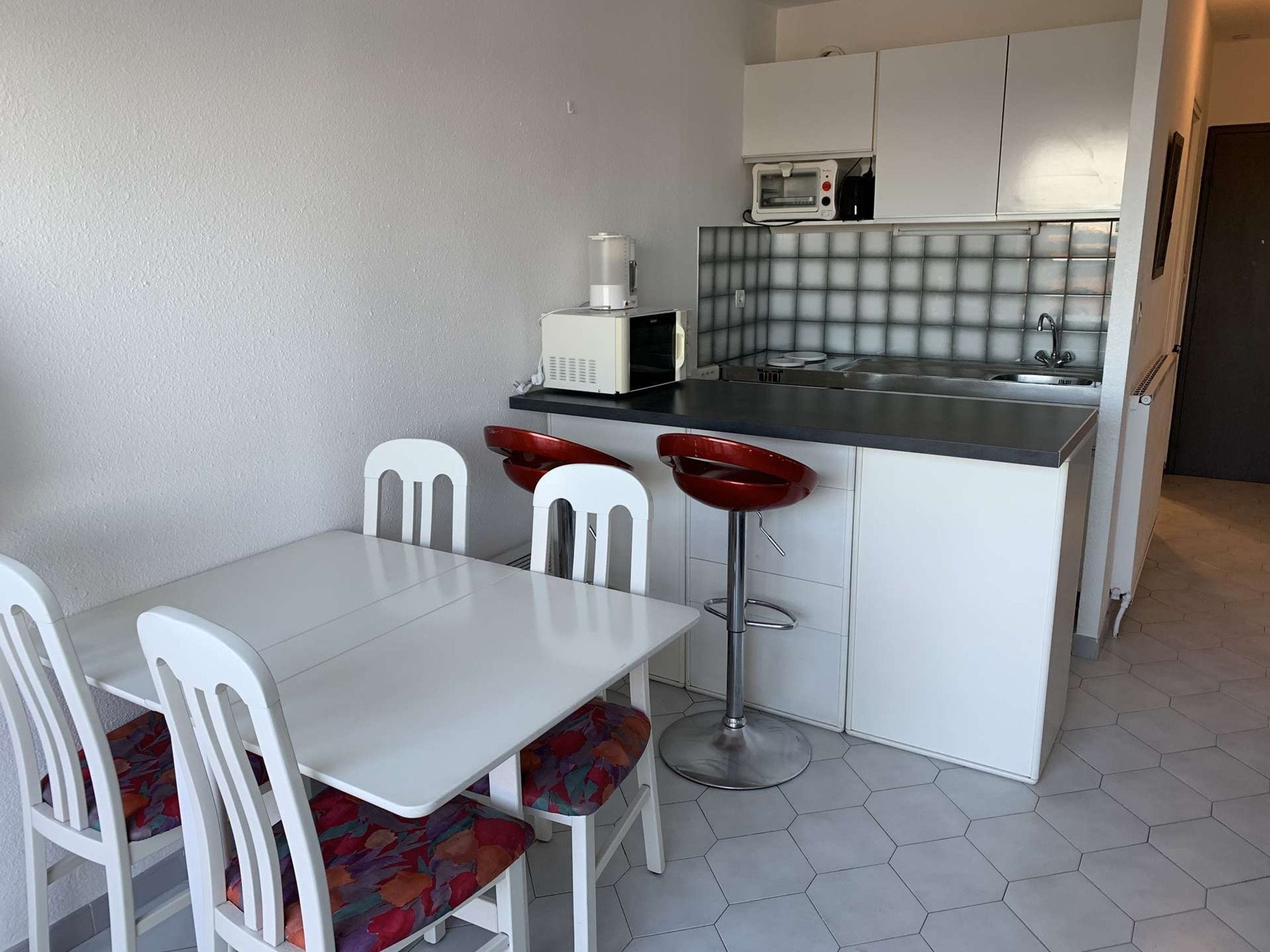 A compact kitchen with a white table and chairs, a microwave, and a sink.