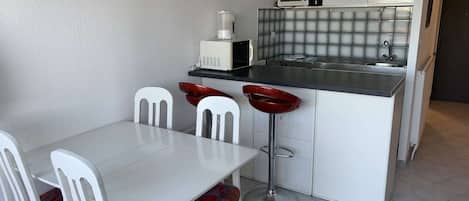 A compact kitchen with a white table and chairs, a microwave, and a sink.