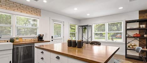 A modern kitchen with white cabinetry, a wooden countertop, and a built-in island.