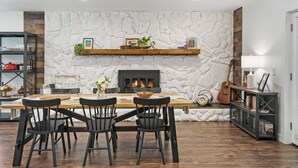 A dining area with a stone wall, a fireplace, and a wooden table with chairs. - Beautiful Kitchen, BBQ, Outdoor Dining, Big Yard (St. Augustine)