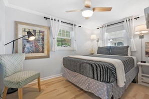 A bedroom with a bed, a chair, a ceiling fan, and a window with curtains. - Qt Cottage on Dunn's Creek, Fire Pit, Kayaks (Satsuma)