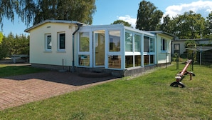 A single-story house with a glass front and a patio area. - Bungalow LAETITIA - In a peaceful central location in Timmendorf Strand. (Insel Poel / OT Timmendorf Strand)