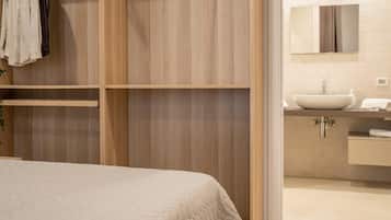 Une chambre à coucher avec un lit, une armoire en bois et une salle de bain équipée d’un lavabo et d’un miroir.