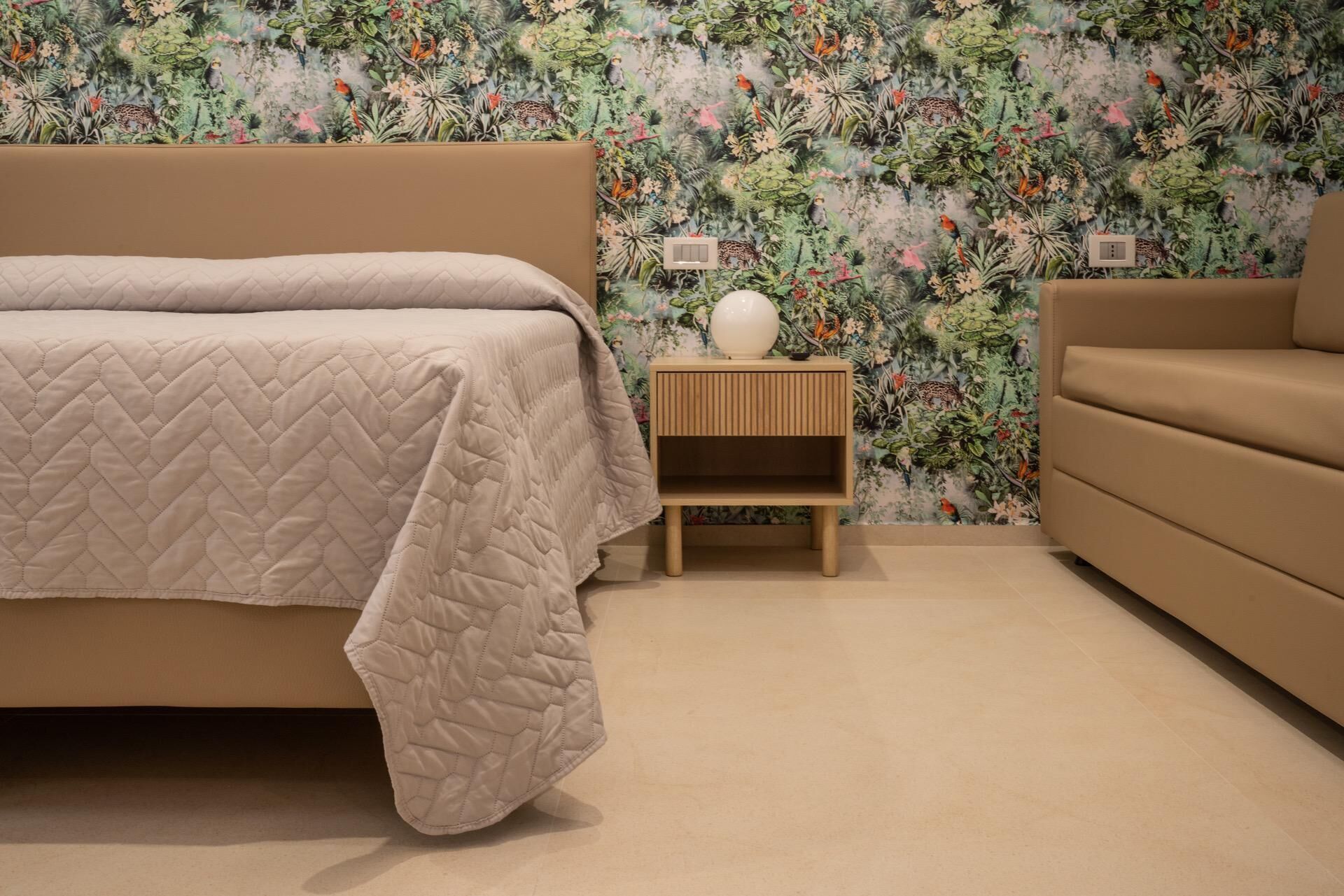 A bedroom with a bed, a nightstand, and a sofa.