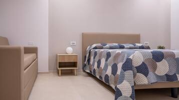 A bedroom with a bed, a nightstand, a lamp, and a chair.