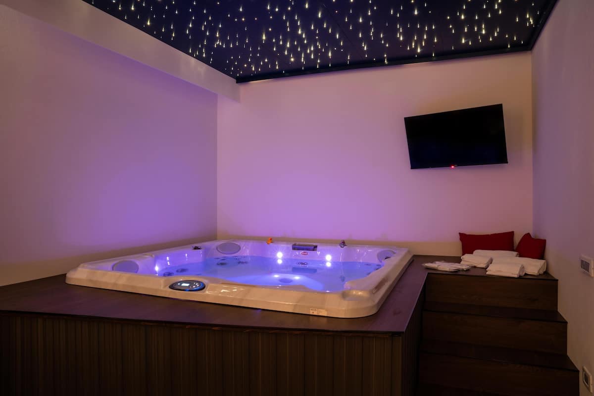 Ein Zimmer mit Whirlpool, Flachbildfernseher und einer Treppe mit Handtüchern.