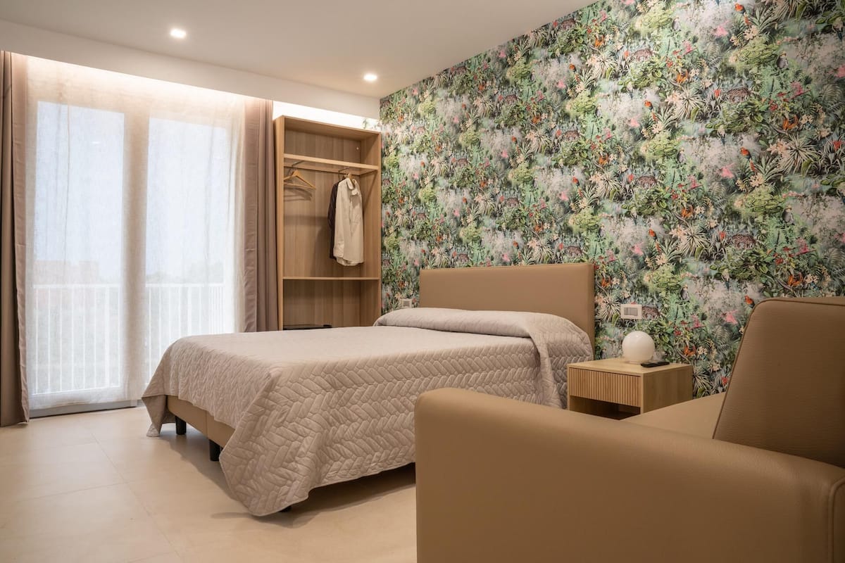Ein Schlafzimmer mit Bett, Kleiderschrank, Sessel und Nachttisch.