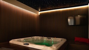 A hot tub in a room with wooden paneling and a starry ceiling.