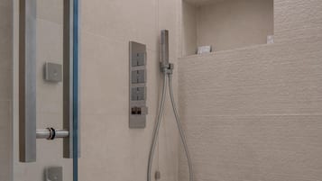 Ein modernes Badezimmer mit Dusche, Bedienfeld und einer kleinen Ablagefläche.