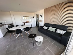 A modern living space with a dining area, a sofa set, and a kitchen.