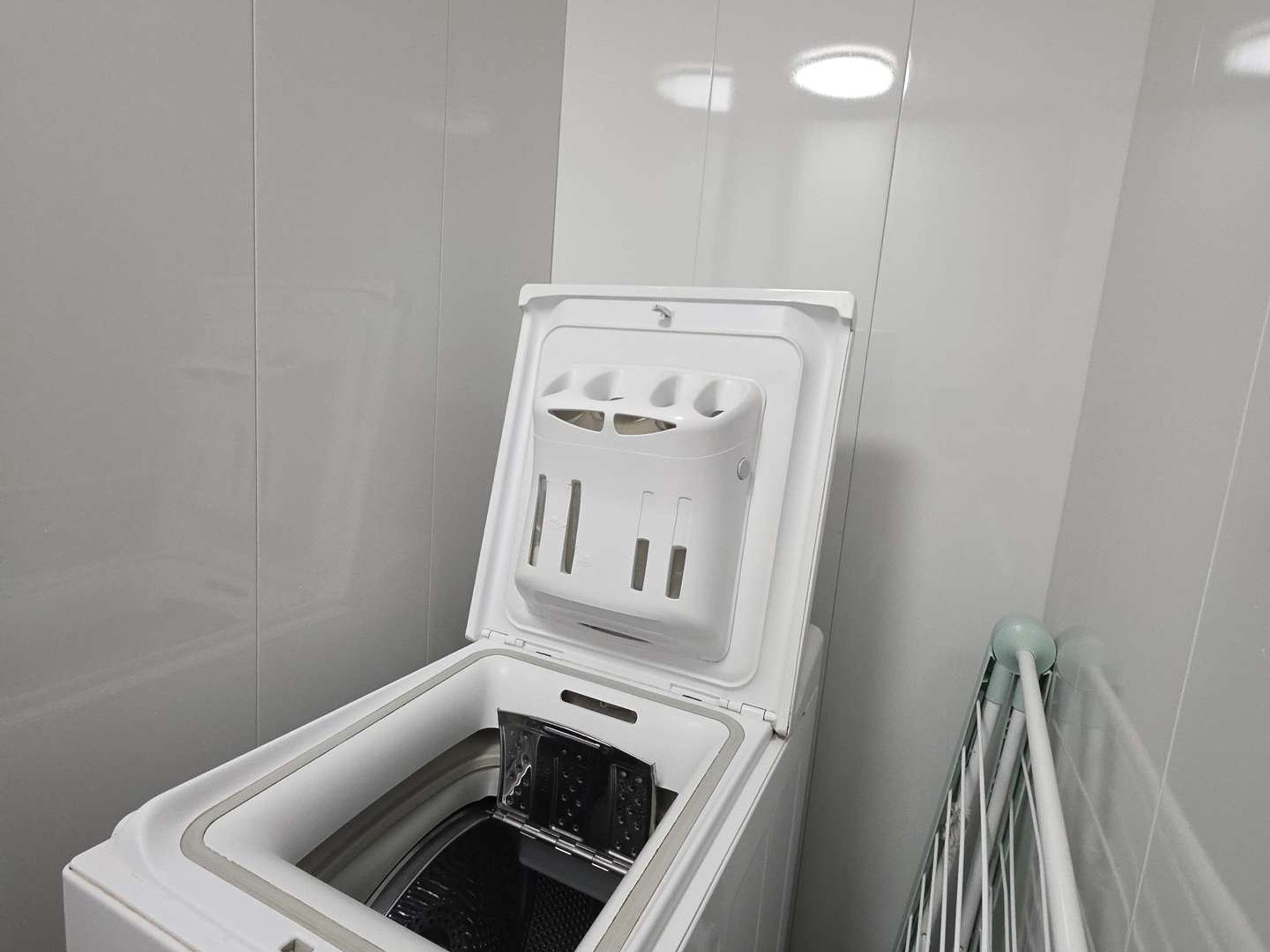 A compact, white, wall-mounted washing machine with a transparent door, allowing visibility of the drum inside.
