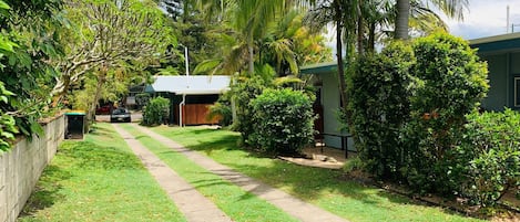 Surrounded by lush greenery, this property offers a serene environment with a well-maintained lawn and a pathway leading to the house.