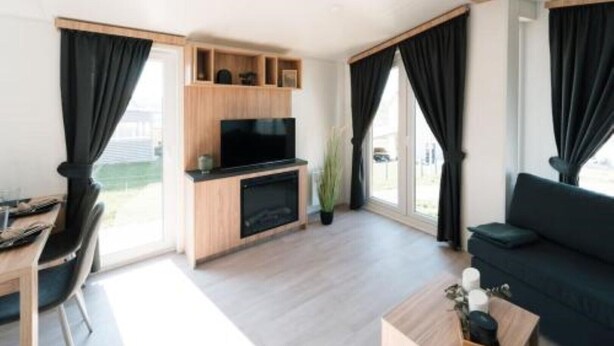A modern living room with a TV, wooden entertainment unit, and a sofa.