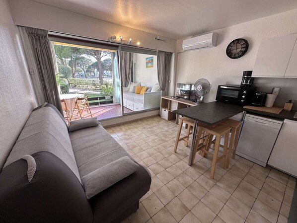 A modern living room with a sofa, a dining table, and a kitchen area with a coffee maker and toaster.