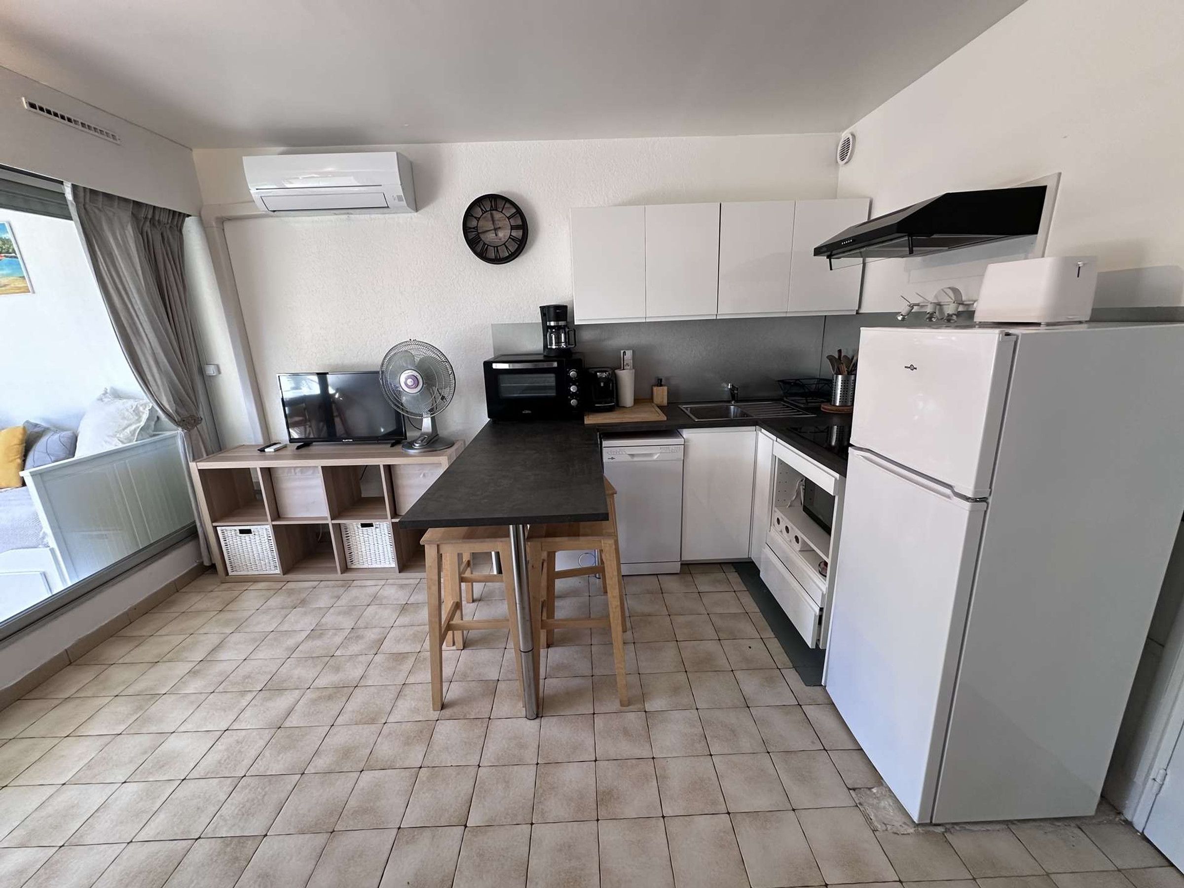 Cozinha compacta com mesa de jantar, micro-ondas, cafeteira e geladeira.