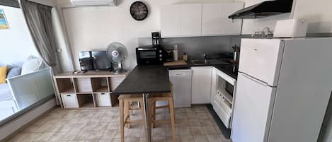 A compact kitchen with a dining table, a microwave, a coffee maker, and a refrigerator.