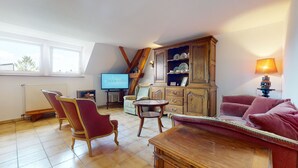 Uma sala de estar aconchegante com televisão, mobiliário de madeira, um sofá vermelho e uma janela com vista.