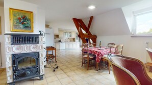 Uma sala de jantar com uma mesa posta para quatro pessoas, uma lareira e uma cozinha ao fundo.