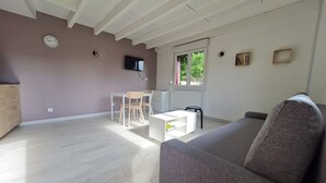 Ein großzügiger Wohnbereich mit einem grauen Sofa, einem weißen Couchtisch und einem an der Wand befestigten Fernseher.