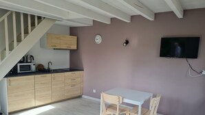 Eine moderne Küche mit Holzausstattung, einer Mikrowelle und einem Spülbecken. Es gibt einen Esstisch mit Stühlen und einen an der Wand montierten Fernseher.
