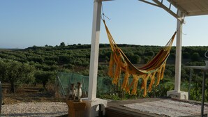 Un hamac sous une pergola blanche, avec vue sur les oliveraies.