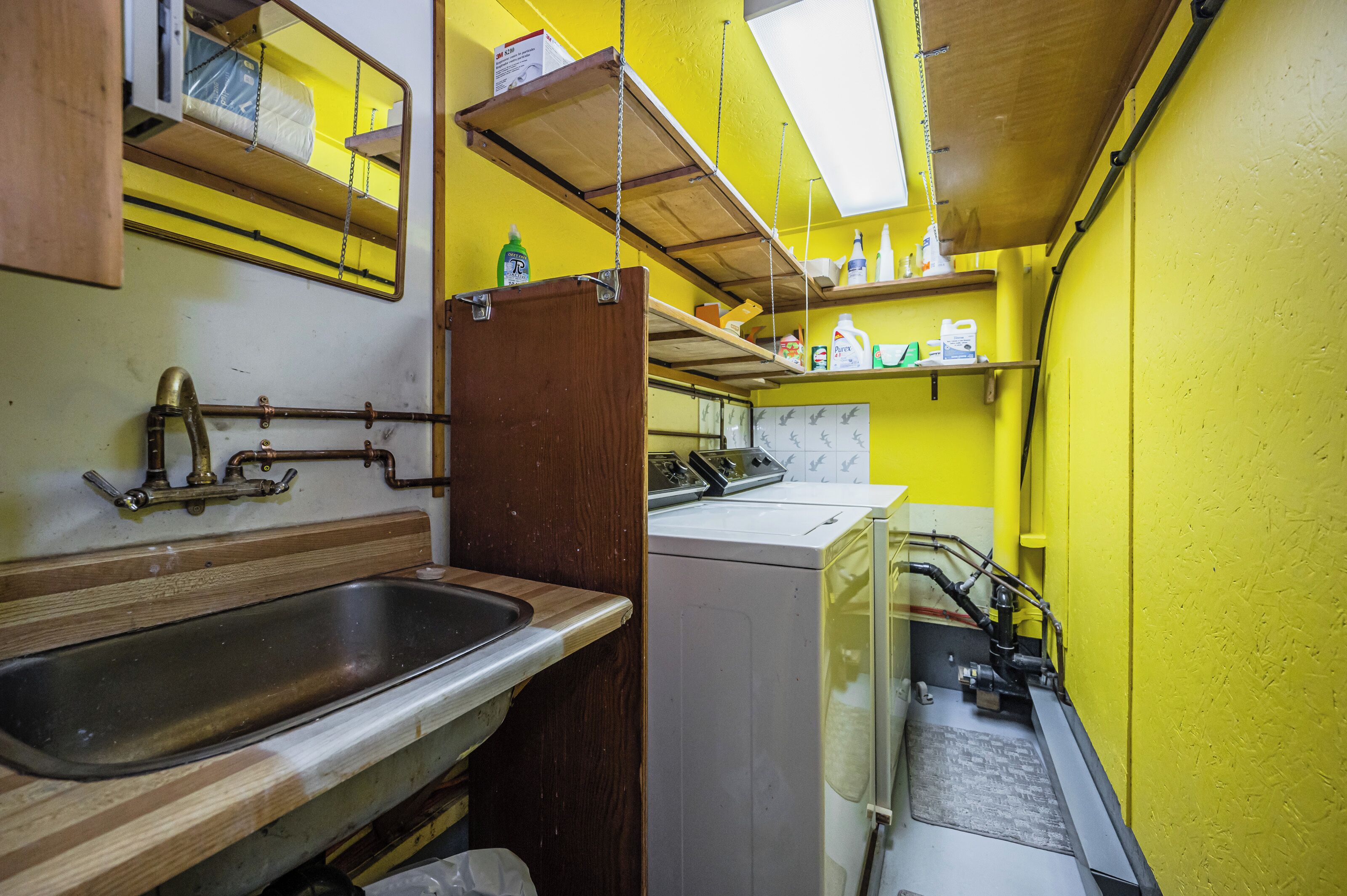 A compact kitchen with a sink, wooden countertop, and a washing machine.