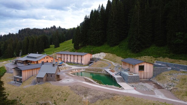 A resort with multiple wooden cabins, a central pool, and a surrounding forested area. - Köpfle Alpe (Balderschwang)