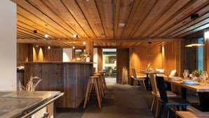 A restaurant with wooden interiors, a bar area, and a dining space with tables and chairs. - Köpfle Alpe (Balderschwang)