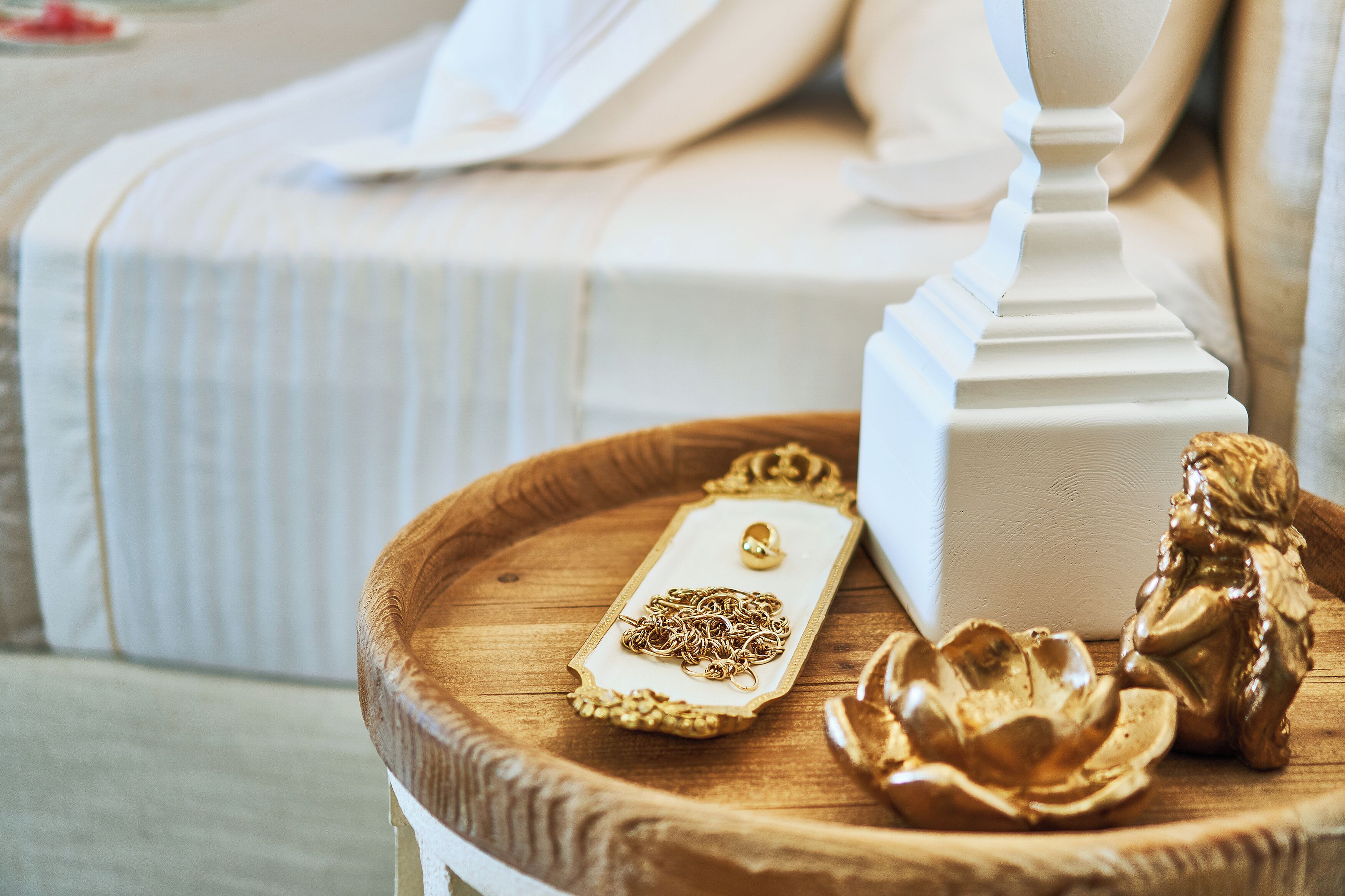 Een houten dienblad met een witte decoratieve doos en een gouden beeldje op een tafel.