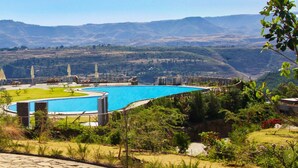 Zona de piscina con vistas a montañas, mobiliario exterior y una estructura cubierta.