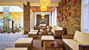 Un vestíbulo con muebles de mimbre, pilares de piedra y una pared decorada con platos coloridos.