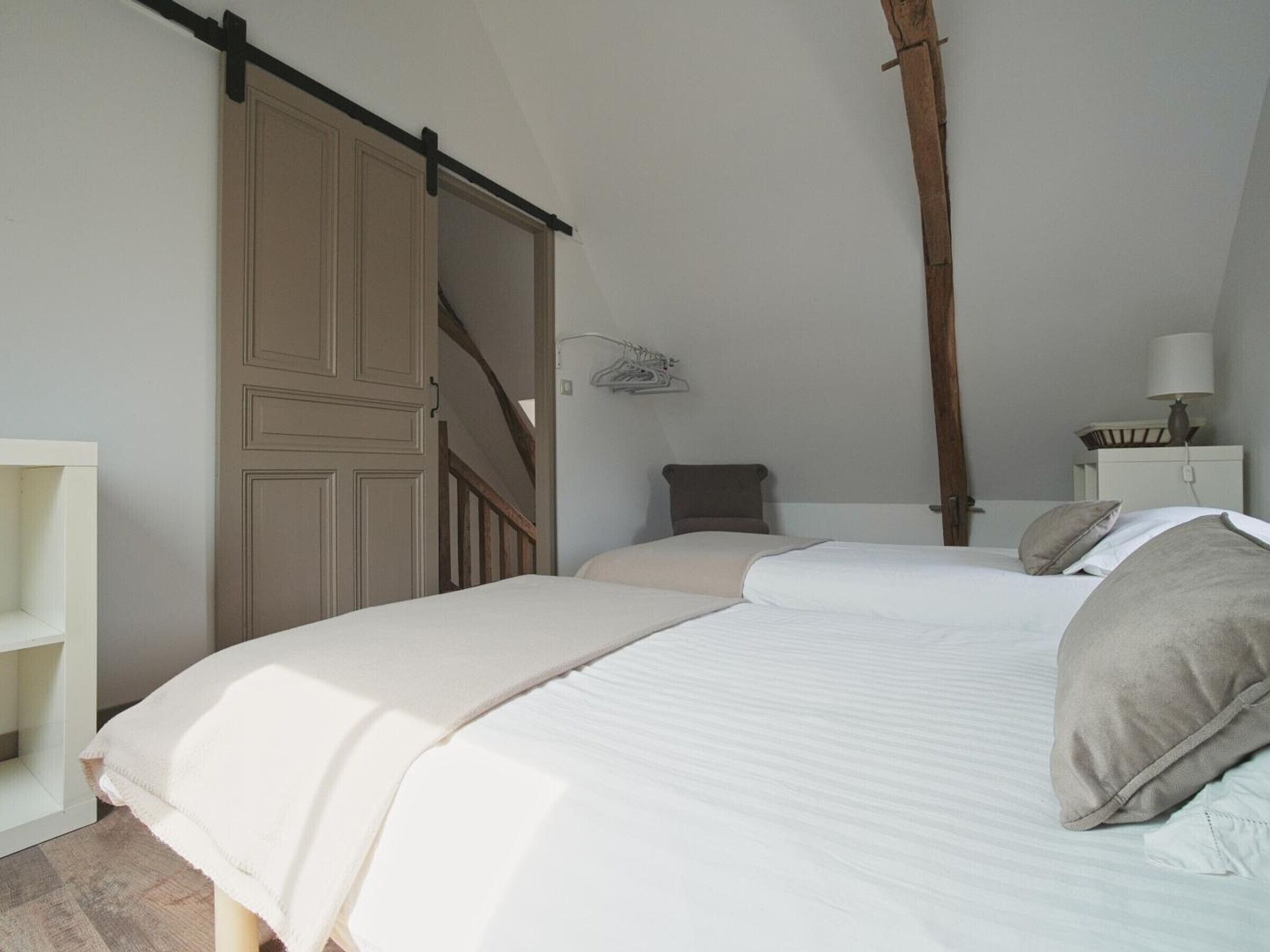 A bedroom with a bed, a wardrobe, a nightstand, and a lamp.