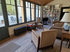 Un salon chaleureux avec une cheminée, une bibliothèque et un coin salon confortable.