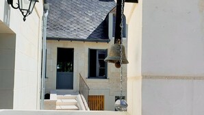 A residential building with a grey tiled roof, a visible front door, and a staircase leading to a wooden deck. - Charming cottage with garden near castles, WiFi, parking included (Benais)