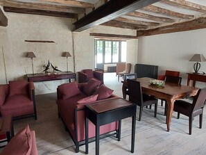 Una habitación amplia con una mesa de comedor rodeada de sillas, un sofá y una pequeña mesa con lámparas.