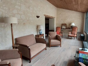 A living room with a sofa, armchairs, a coffee table, and lamps. There is a fireplace and a window with a view.