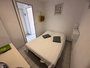 A small, clean room with a bed, a desk, and a door leading to another room. - 2-room apartment with terrace and parking in Le Grau-du-Roi for 4 people (Le Grau-du-Roi)