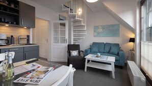A modern kitchen with grey cabinets, a white spiral staircase, a blue sofa, and a white coffee table.