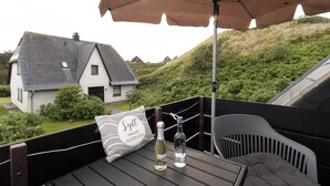 A wooden deck with a table, two bottles, and a pillow with text.