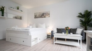 A modern bedroom with a bed, bedside table, and a sofa. - Hochwertiges 1-zi-app für 2+1 Pers. am See, Wlan, Terrasse, Elektr. Kamin (Mirow)