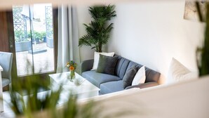 A modern living room with a grey sofa, white coffee table, and a potted plant. - Hochwertiges 1-zi-app für 2+1 Pers. am See, Wlan, Terrasse, Elektr. Kamin (Mirow)