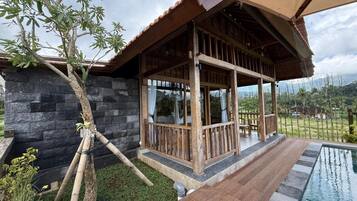 A wooden structure with a stone wall, a pool, and a view of the surrounding landscape.