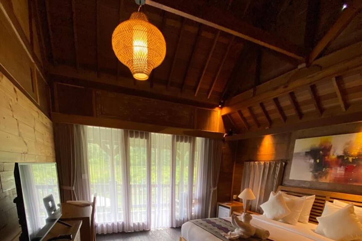 Une chambre avec un plancher en bois, un lit, un bureau et un téléviseur.